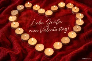 Herz aus brennenden Teelichtern auf rotem Stoff, Text: Liebe Grüße zum Valentinstag!