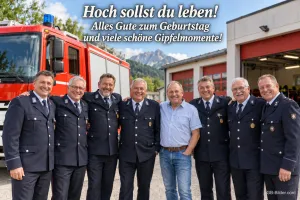 Gruppe von Feuerwehrleuten in Uniform vor einem Feuerwehrauto und den Bergen, Text: Hoch sollst du leben! Alles Gute zum Geburtstag und viele schöne Gipfelmomente!