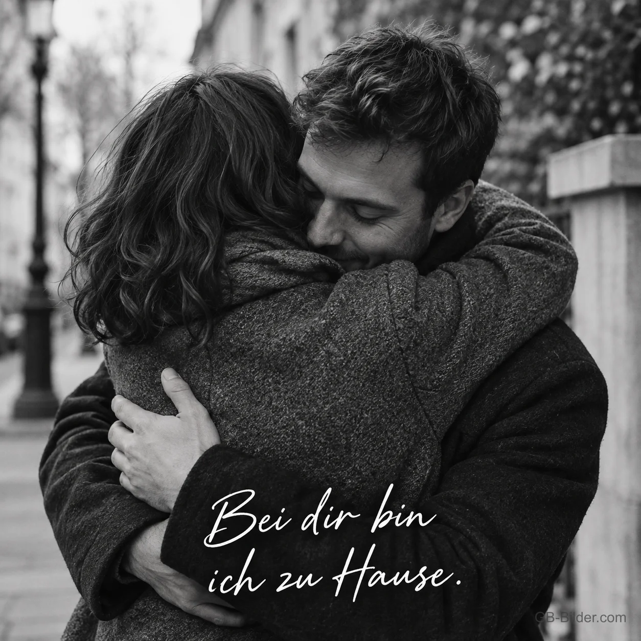 Paar umarmt sich auf der Straße im Schwarz-Weiß-Foto, Text: Bei dir bin ich zu Hause. Paar umarmt sich auf der Straße im Schwarz-Weiß-Foto, Text: Bei dir bin ich zu Hause.