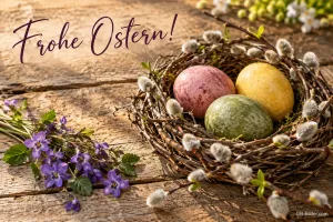 Nest aus Weidenkätzchen mit bunten Ostereiern auf Holz, Text: Frohe Ostern!