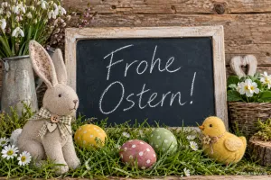 Stoffhase vor der Kreidetafel, Text: Frohe Ostern