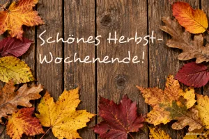 Herbstblätter auf Holzbrettern, Text: Schönes Herbst-Wochenende!
